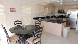 A modern kitchen with a central island, black dining table, and chairs.