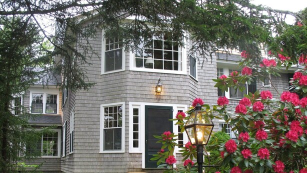 A two-story house with a grey exterior, white trim, and a black front door. - Harbourside Inn (Northeast Harbor)