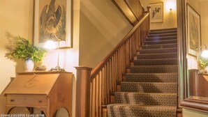 A staircase with patterned carpet, wooden railings, and wall-mounted lighting. - Harbourside Inn (Northeast Harbor)