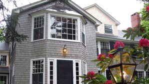 A two-story house with a bay window, a front door, and a small porch.