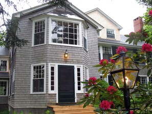 A two-story house with a bay window, a front door, and a small porch.