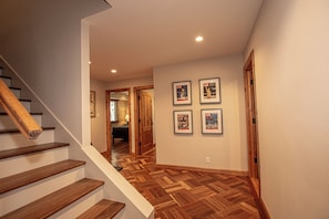 A staircase leading to a room with wooden flooring and framed pictures on the wall.