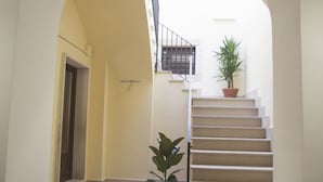 A staircase with a potted plant on the landing, a door at the bottom, and a window at the top. - L'Antico Monastero (Sant'Agata di Puglia)