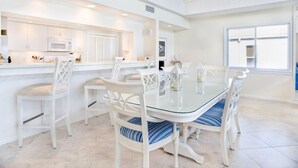 Una cocina moderna con armarios blancos, una mesa de comedor de vidrio y sillas a rayas azules.