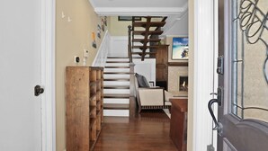 Una escalera de madera que lleva a una sala de estar con chimenea, un sofá y una mesa de centro.