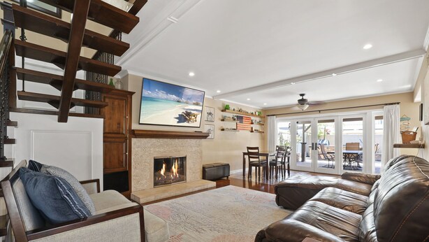 Un salón amplio con chimenea, sofá de cuero y un televisor grande montado sobre él.