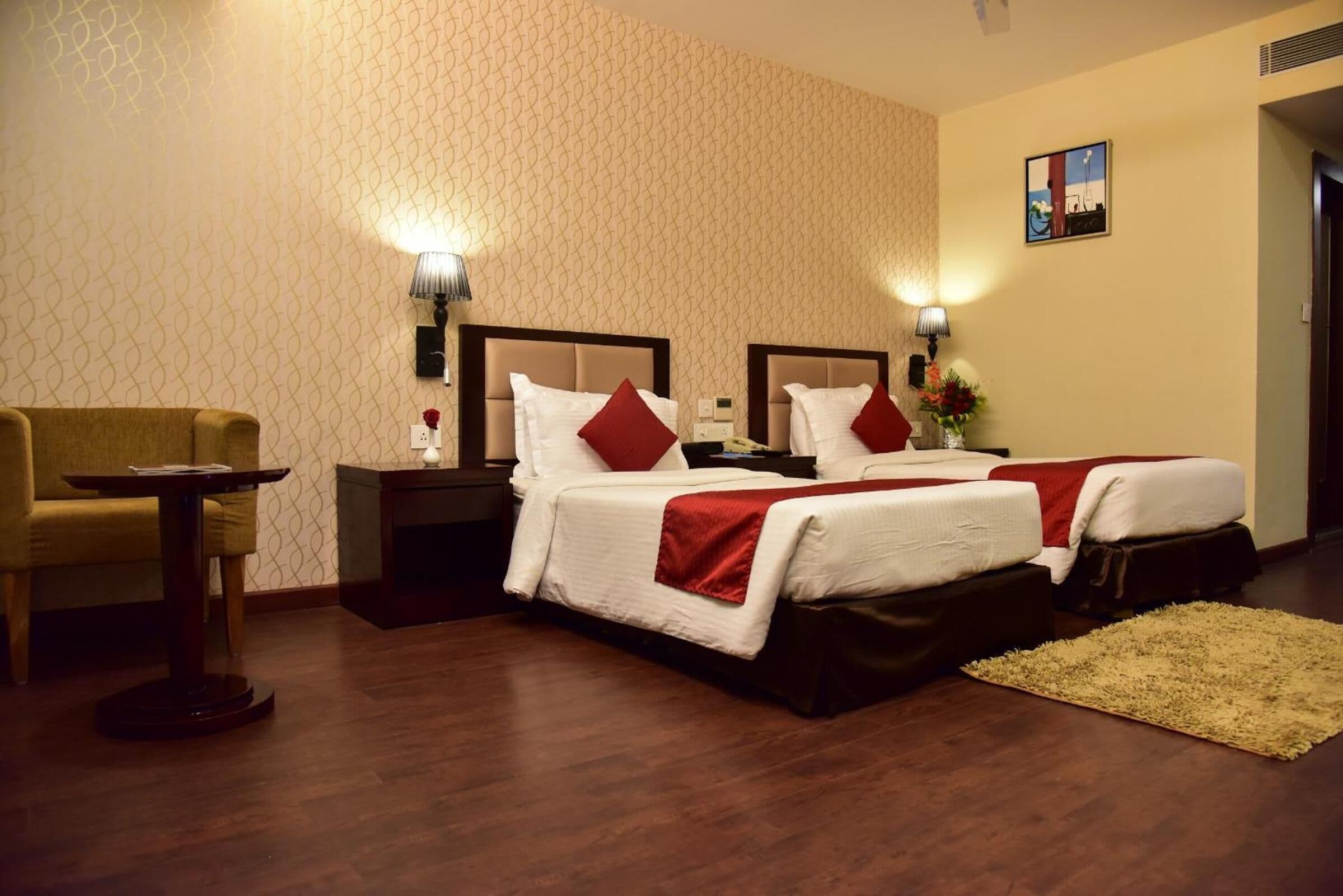 Ein Hotelzimmer mit zwei Betten, einem kleinen Tisch, einem Stuhl und einer Lampe.