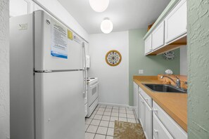 Una cocina compacta con refrigerador, estufa y lavamanos.