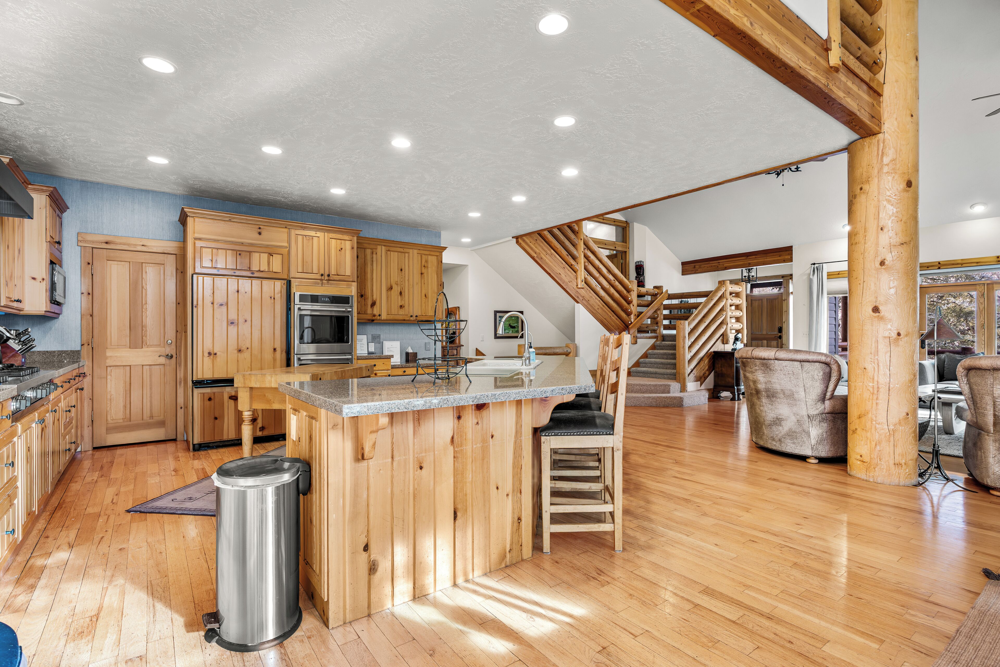 A spacious kitchen with wooden cabinets, a central island, and a staircase leading to a loft area.