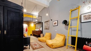 A room with a black wardrobe, yellow bean bag chairs, a ladder, and a radiator. - Funky Flat (Sofia)