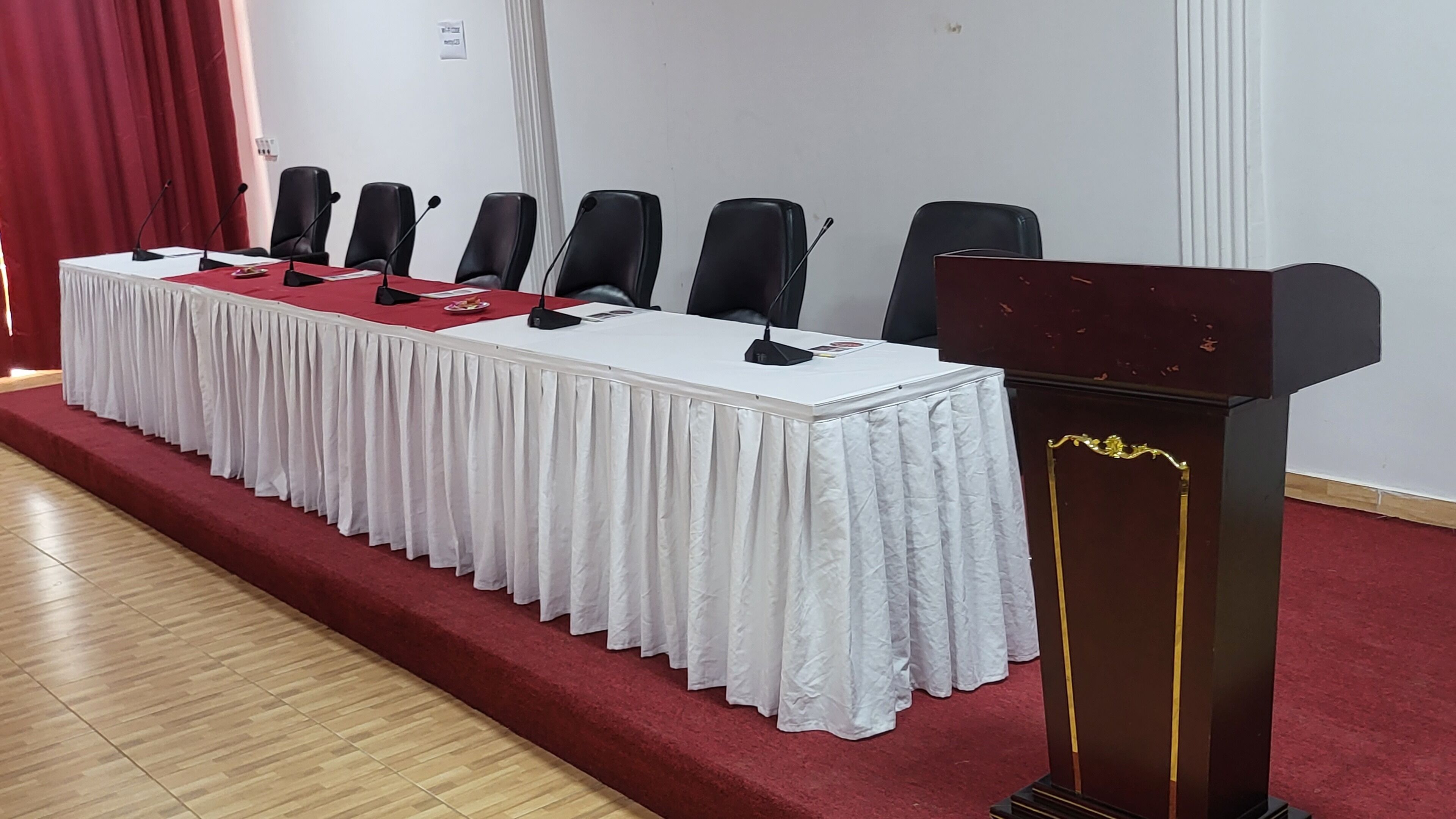 A conference room with a long table, six chairs, and a podium.