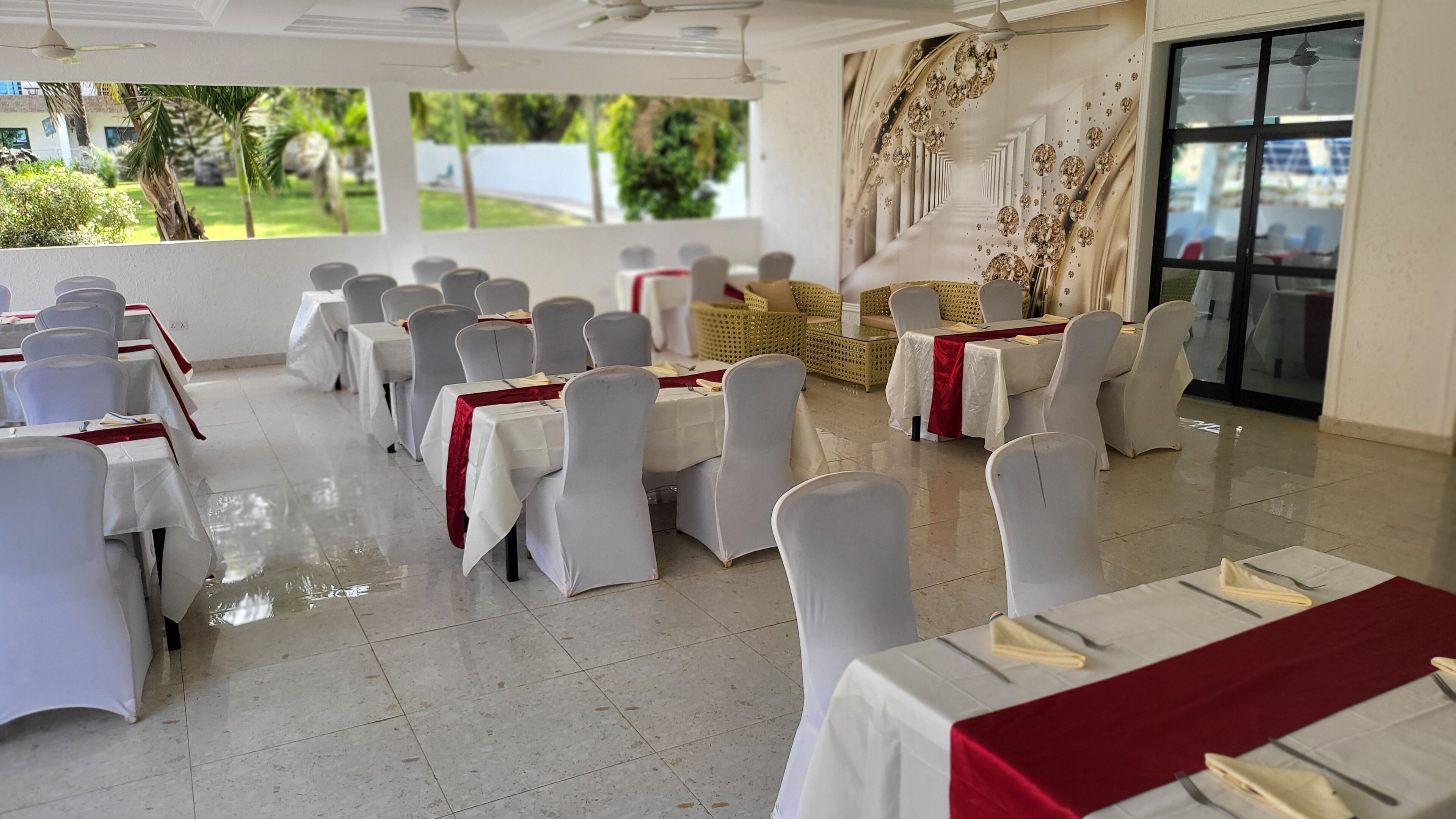A banquet hall with rows of tables, white tablecloths, and grey chairs.