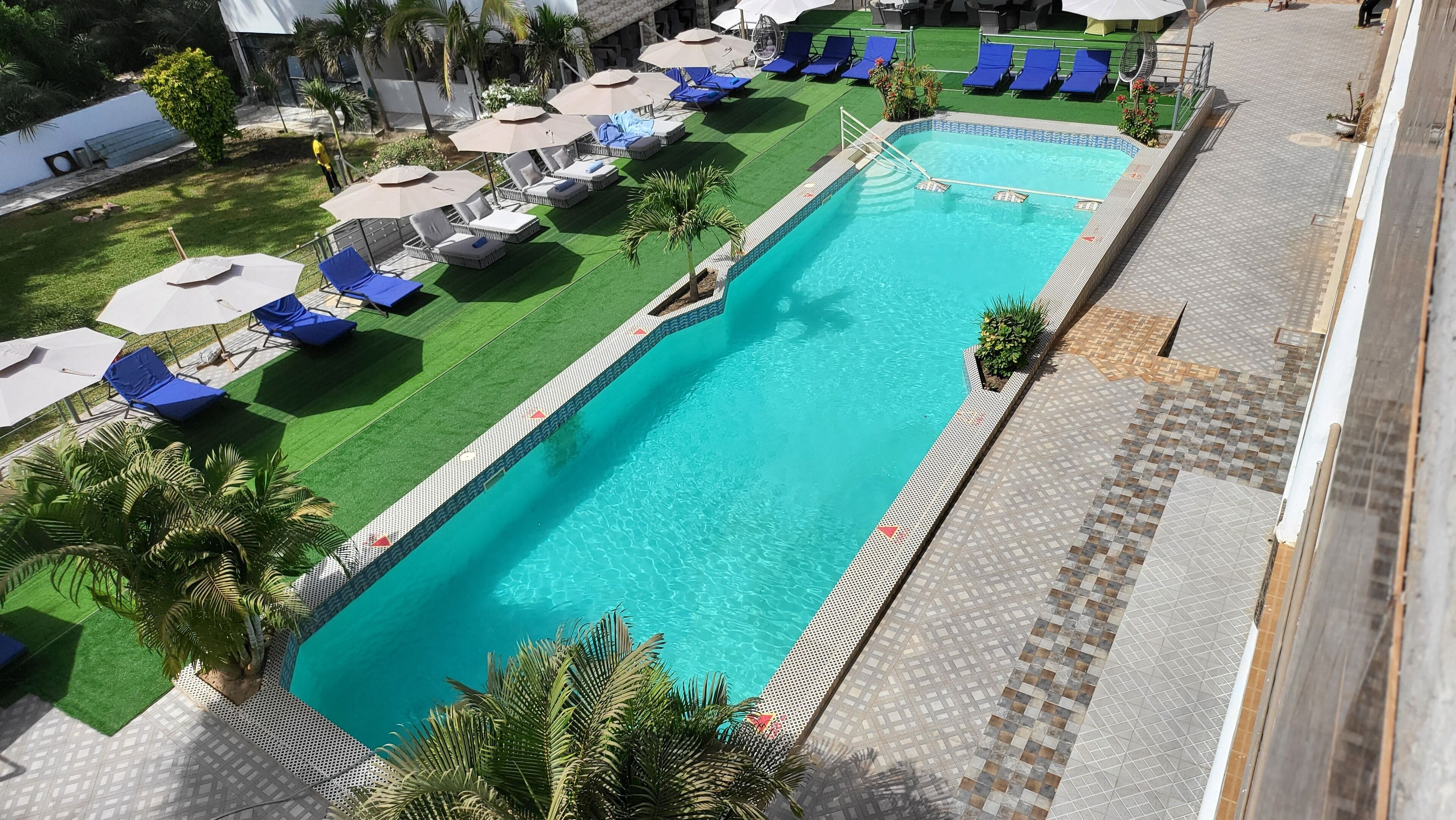 Una piscina con agua azul, rodeada de sillas de descanso y sombrillas.