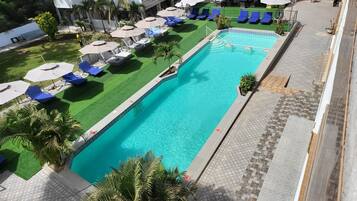 A swimming pool with blue water, surrounded by lounge chairs and umbrellas.