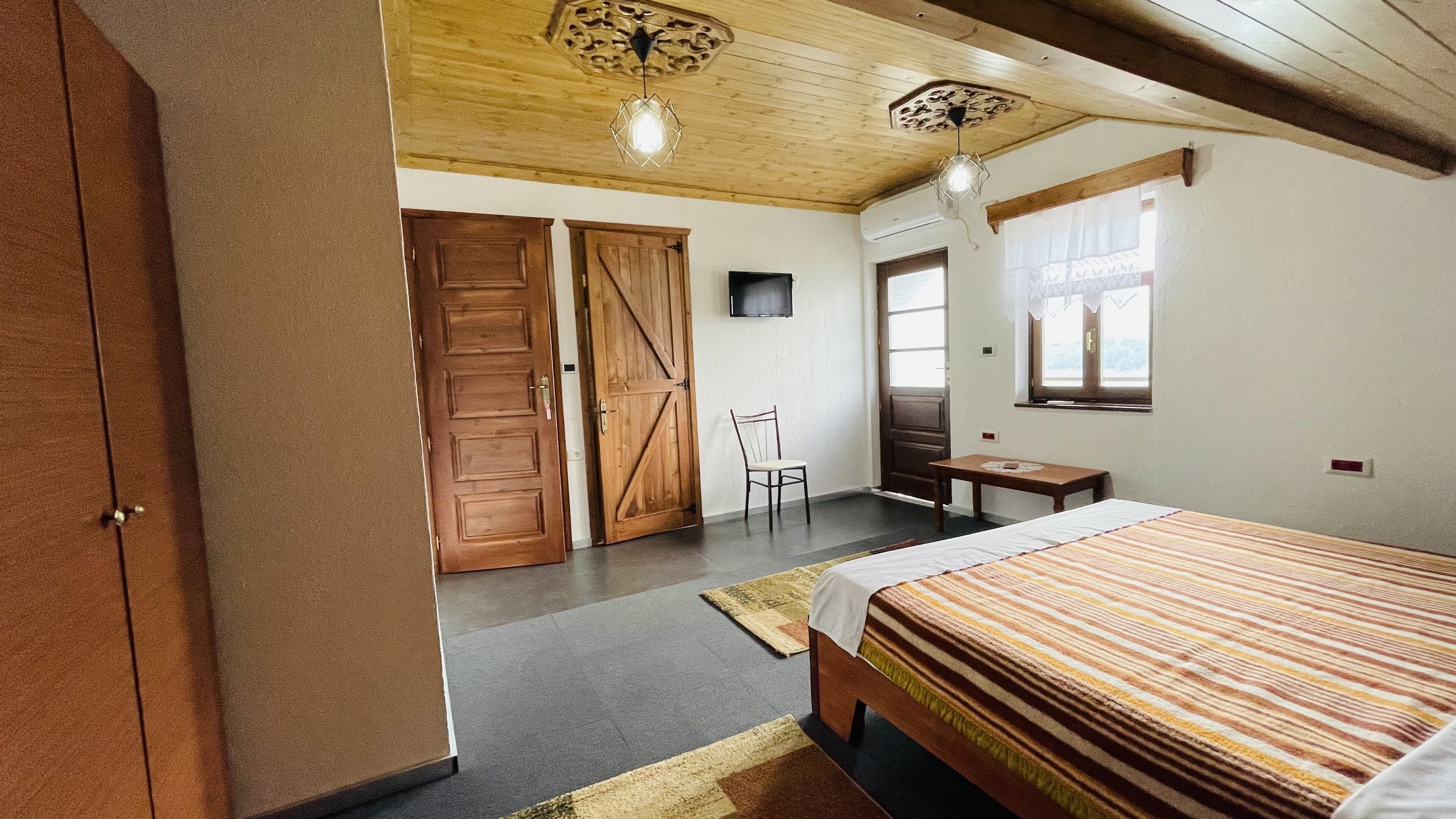 Un dormitorio con cama, escritorio, silla y dos puertas de madera.