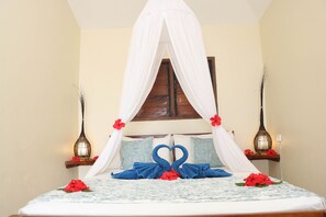 A bed with a canopy, decorative pillows, and a heart-shaped towel arrangement. - Blue Bay Resort (Mele)