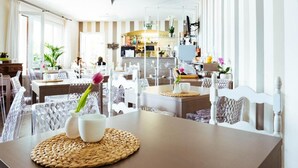 A modern dining area with clear glass chairs and tables, a central buffet, and a view of the kitchen in the background. - Albergo Sole (Cannero Riviera)