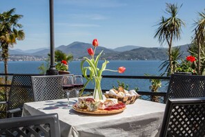 A table set with a cheese board, wine glasses, and tulips by a scenic waterfront.