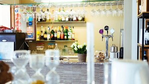 A bar area with a variety of bottles and glasses, a cash register, and a potted plant. - Albergo Sole (Cannero Riviera)