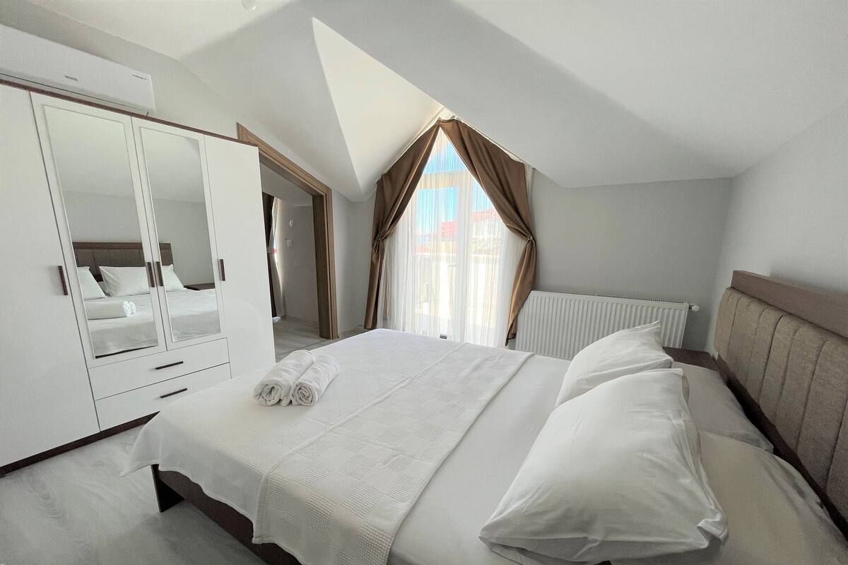 A bedroom with a bed, a wardrobe, and a window with curtains.
