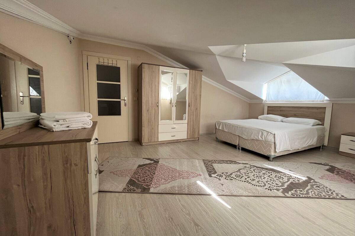 A bedroom with a bed, a wardrobe, a mirror, and a ceiling fan.
