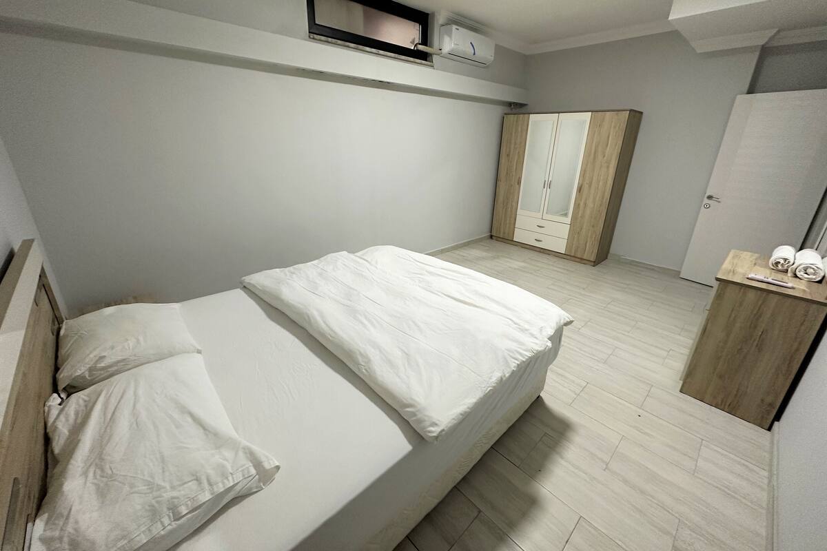A bedroom with a bed, a wardrobe, and a small shelf with towels.