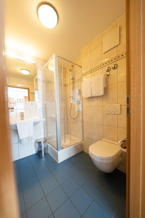 A bathroom with a glass-enclosed shower, a toilet, and a sink. - ates Hotel Straßburg - Kehl (Kehl)