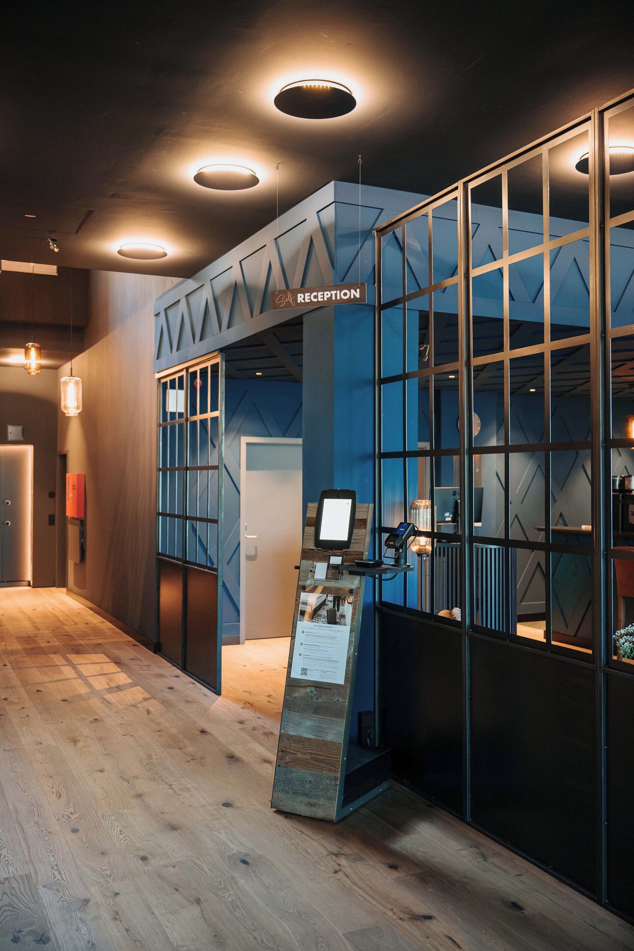 Un espace d’accueil au design moderne, comprenant un comptoir d’accueil, un kiosque d’information numérique et un panneau d’affichage.