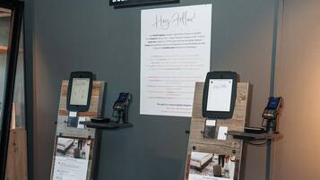 A self-check-in kiosk with a sign above it, a digital display, and a payment terminal.