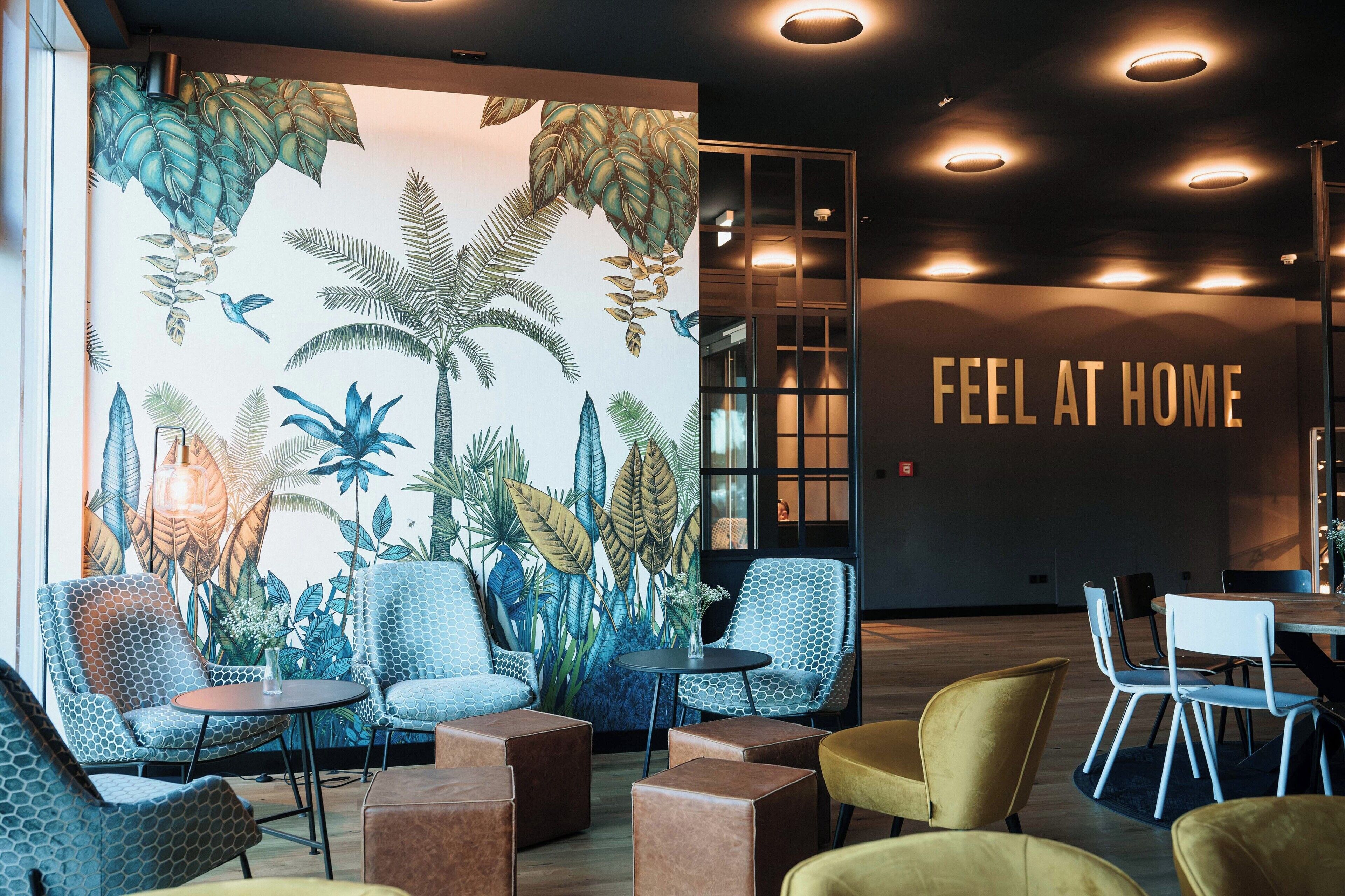 A modern interior with seating, a mural, and a 'FEEL AT HOME' sign.