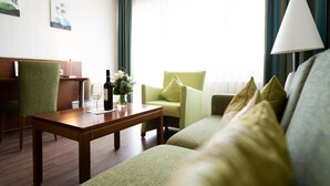 A hotel room with a wooden coffee table, a green sofa, a green armchair, and a lamp. - ates Hotel Straßburg - Kehl (Kehl)