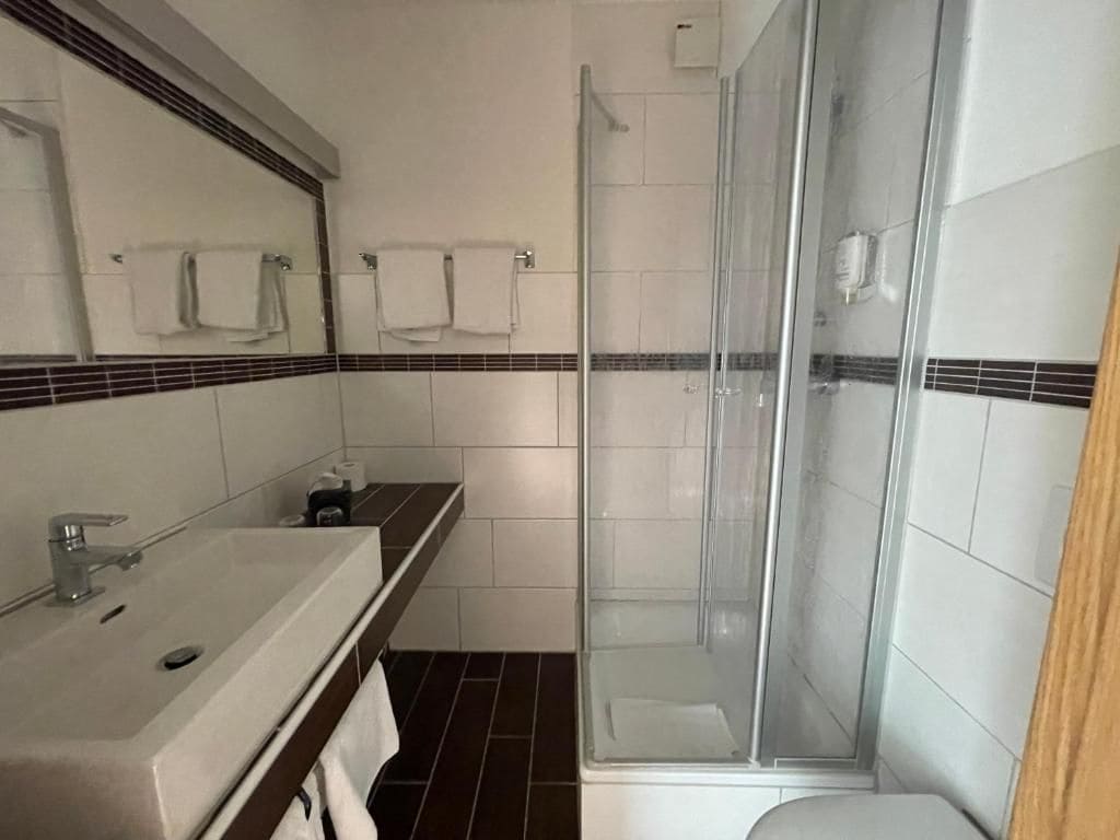 Ein Badezimmer mit Dusche, Waschbecken und Spiegel.