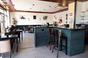 A modern bar area with a central island, seating, and a bar counter. - Europa Hotel (Kehl)