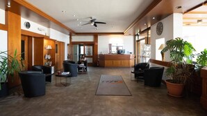 A hotel lobby with a reception desk, seating area, and a large plant. - Europa Hotel (Kehl)