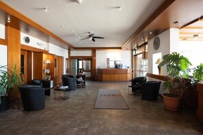A hotel lobby with a reception desk, seating area, and a large plant. - Europa Hotel (Kehl)