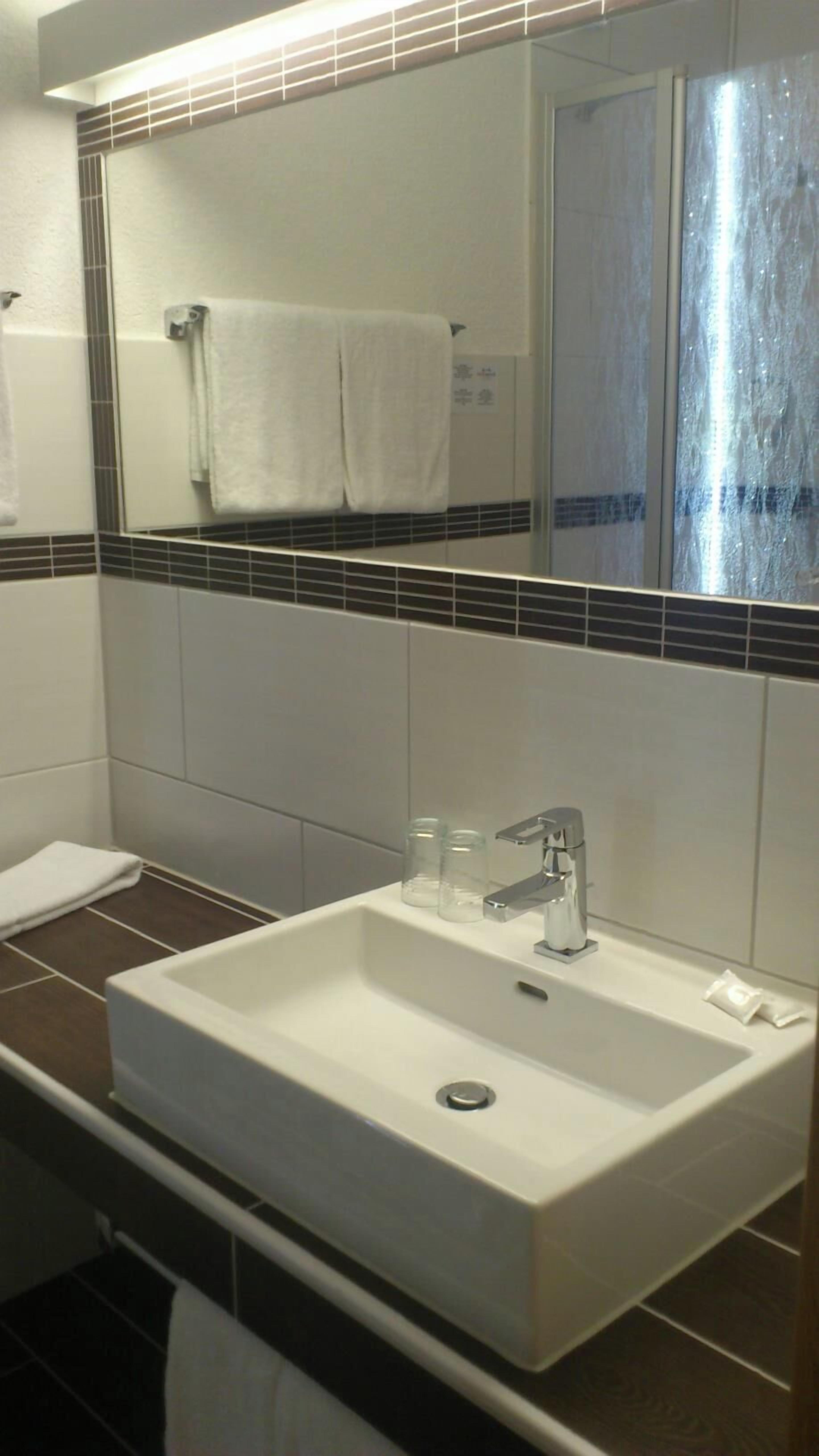 A bathroom with a white sink, a mirror, and a towel rack.