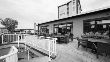 A hotel with outdoor seating, a staircase, and a sign indicating it is a hotel.