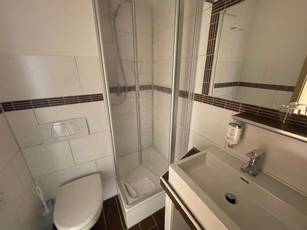 A bathroom with a shower, toilet, and sink.