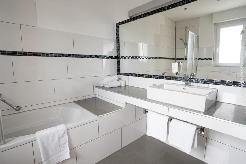 Une salle de bain moderne avec une baignoire, deux lavabos et un grand miroir.