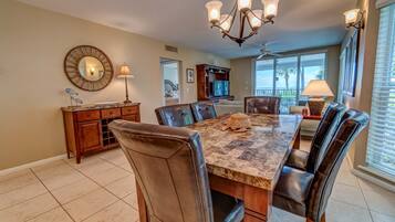A dining room with a large marble table, leather chairs, a chandelier, and a view of the outdoors.
