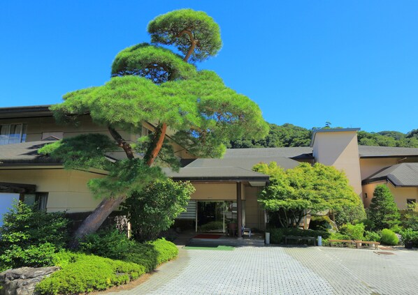 Ein traditionelles japanisches Haus mit einem gepflegten Garten, darunter eine markante Kiefer.