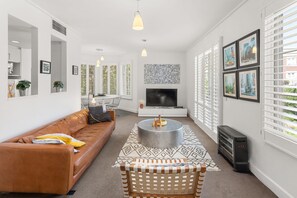 A modern living room with a leather sofa, a coffee table, and a TV.