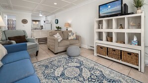 A living room with a TV, sofas, a coffee table, and a patterned rug. - Oceanfront condos with 3 night minimum rentals and linens included! (Ocean City)
