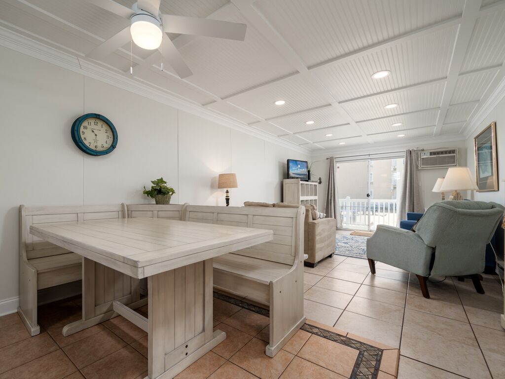 A spacious room with a wooden dining table and bench, a television, and a ceiling fan.