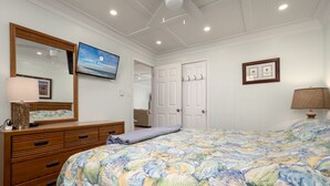 A bedroom with a large bed, a dresser, a television, and a ceiling fan. - Oceanfront condos with 3 night minimum rentals and linens included! (Ocean City)