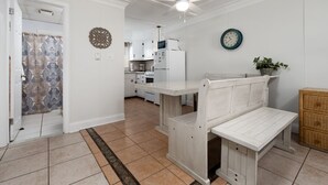 A kitchen with white cabinets, a microwave, and a refrigerator. There is a bench in the center of the room. - Oceanfront condos with 3 night minimum rentals and linens included! (Ocean City)