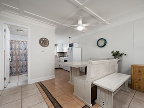A kitchen with white cabinets, a microwave, and a refrigerator. There is a bench in the center of the room. - Oceanfront condos with 3 night minimum rentals and linens included! (Ocean City)