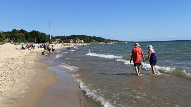 Una playa con gente caminando por la orilla y un cielo despejado.