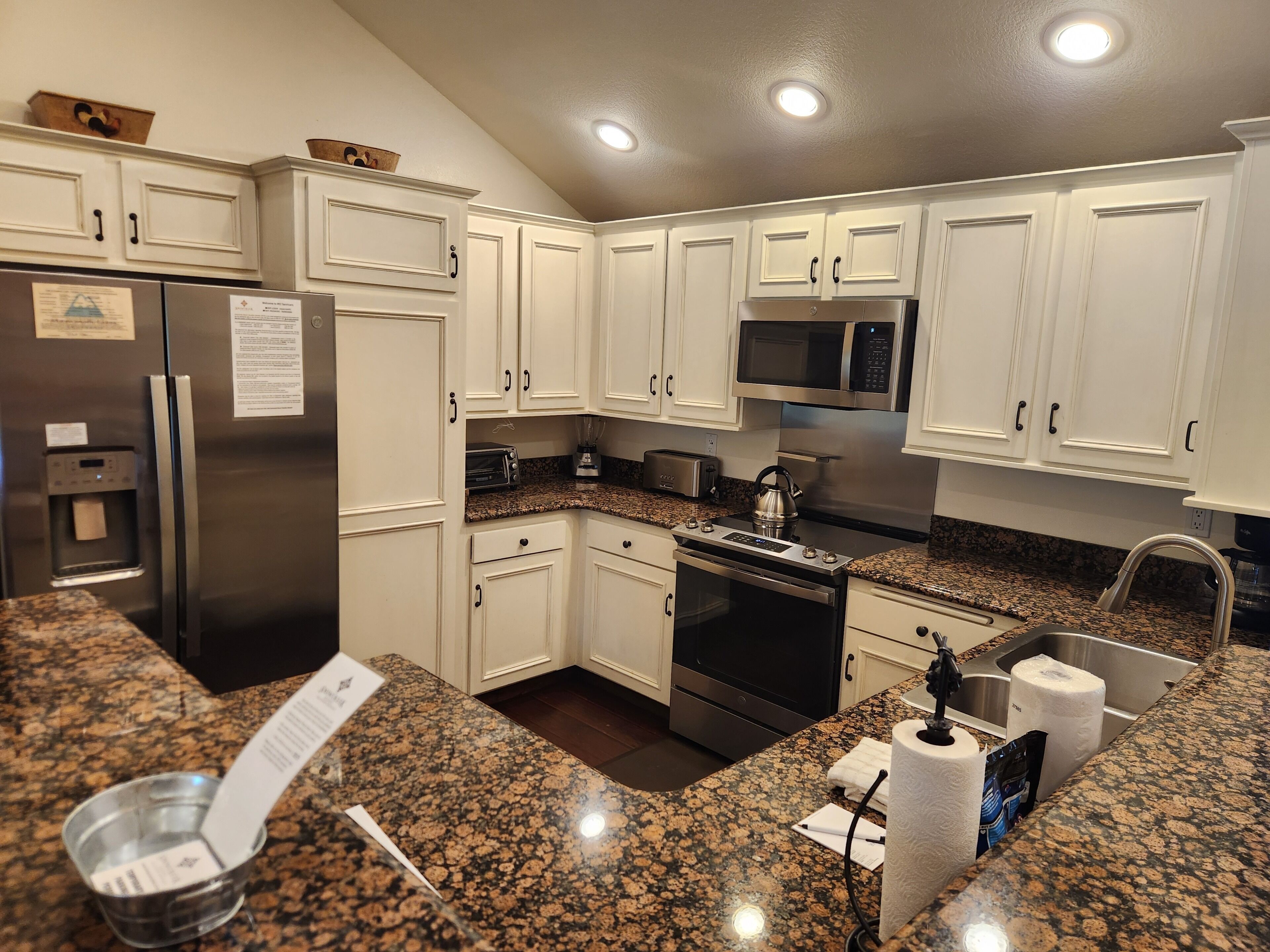 A kitchen with white cabinets, stainless steel appliances, granite countertops, and a built-in oven.