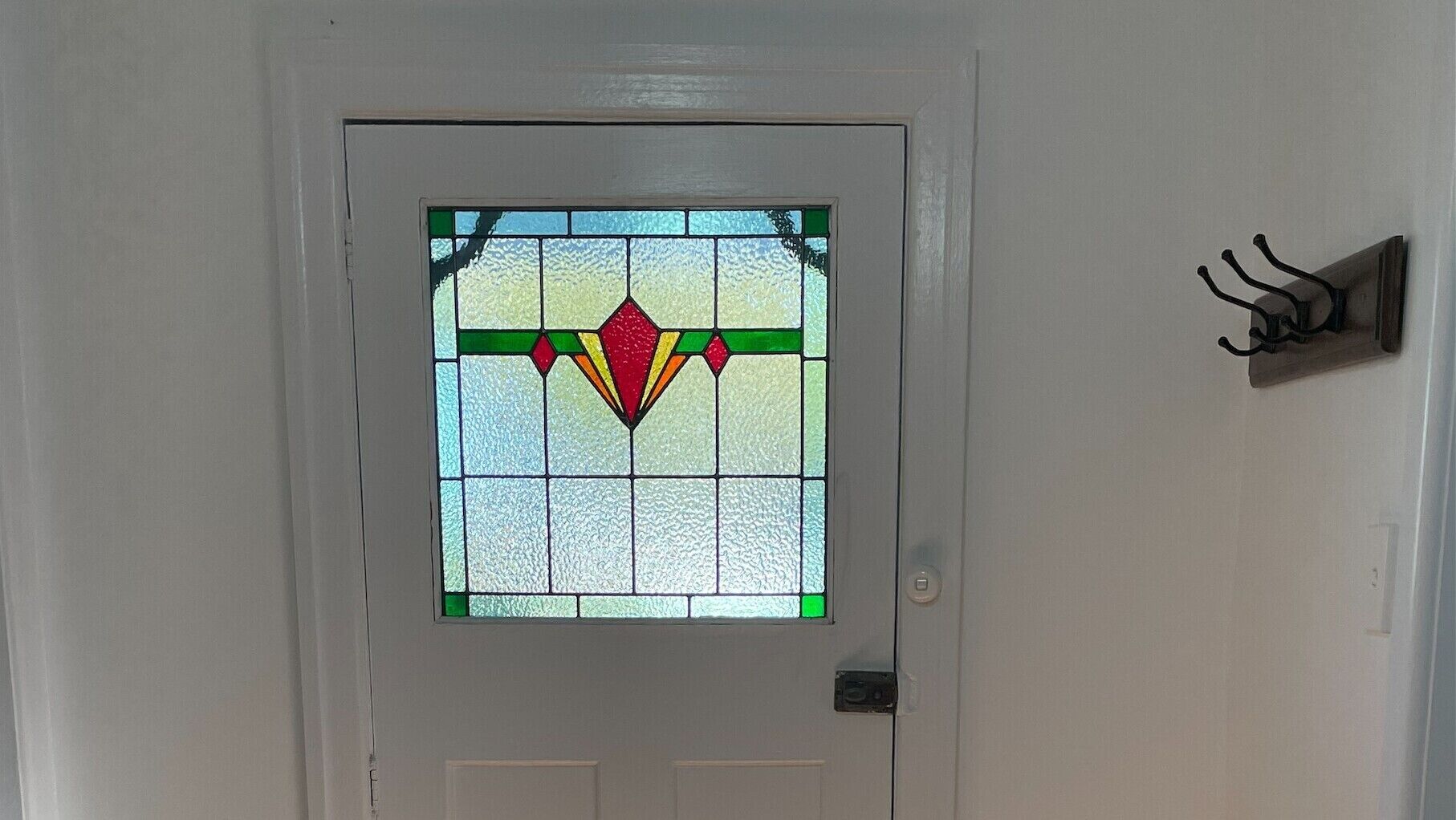 A white door with a stained glass window featuring a geometric design.